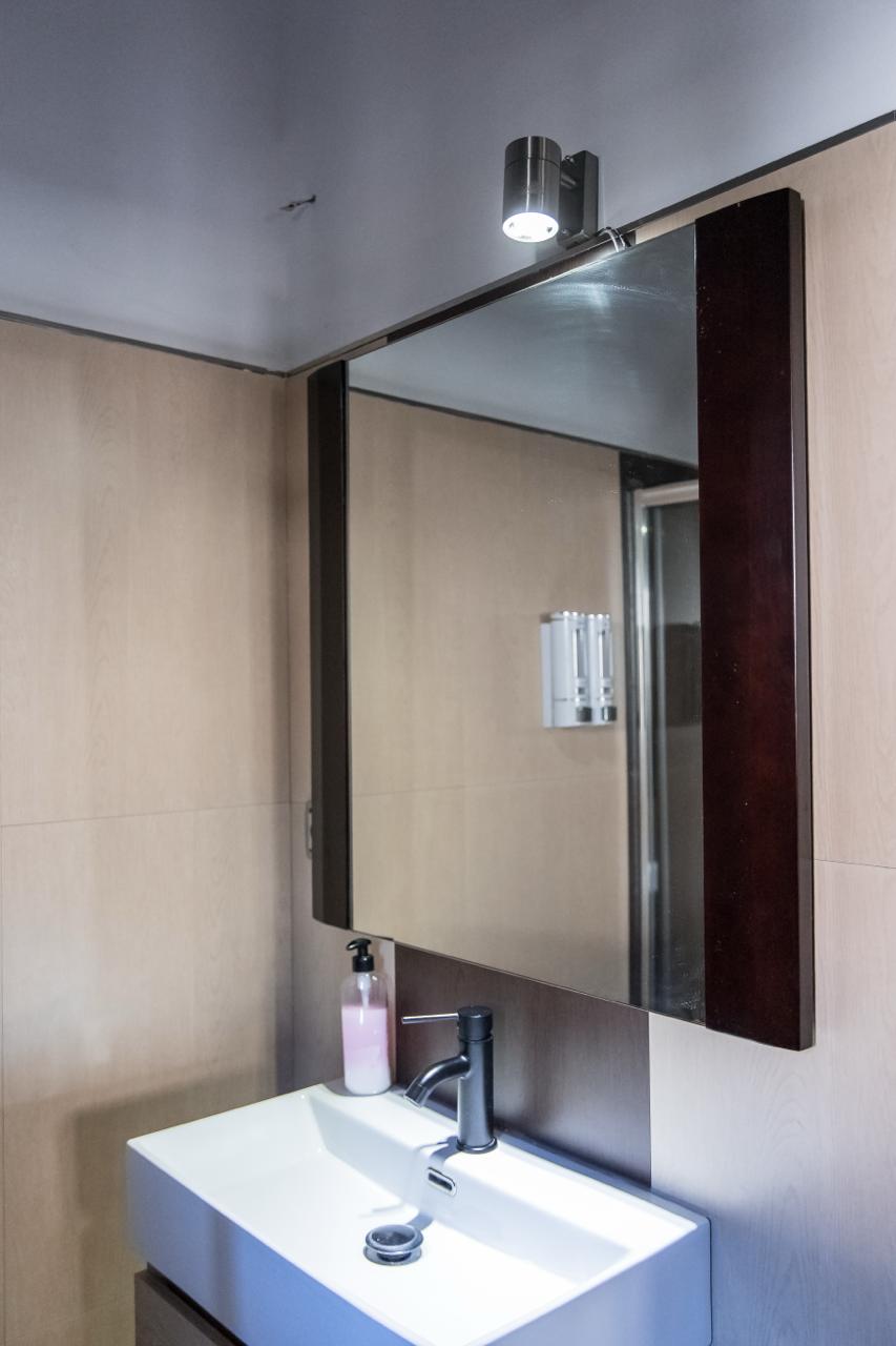 Bathroom with light wood panelling, basin and mirror.