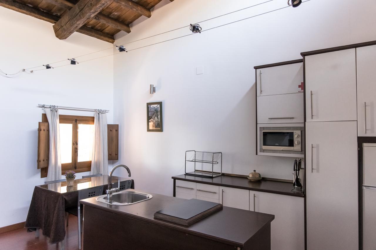 Apartment kitchen with island, sink and shuttered window.