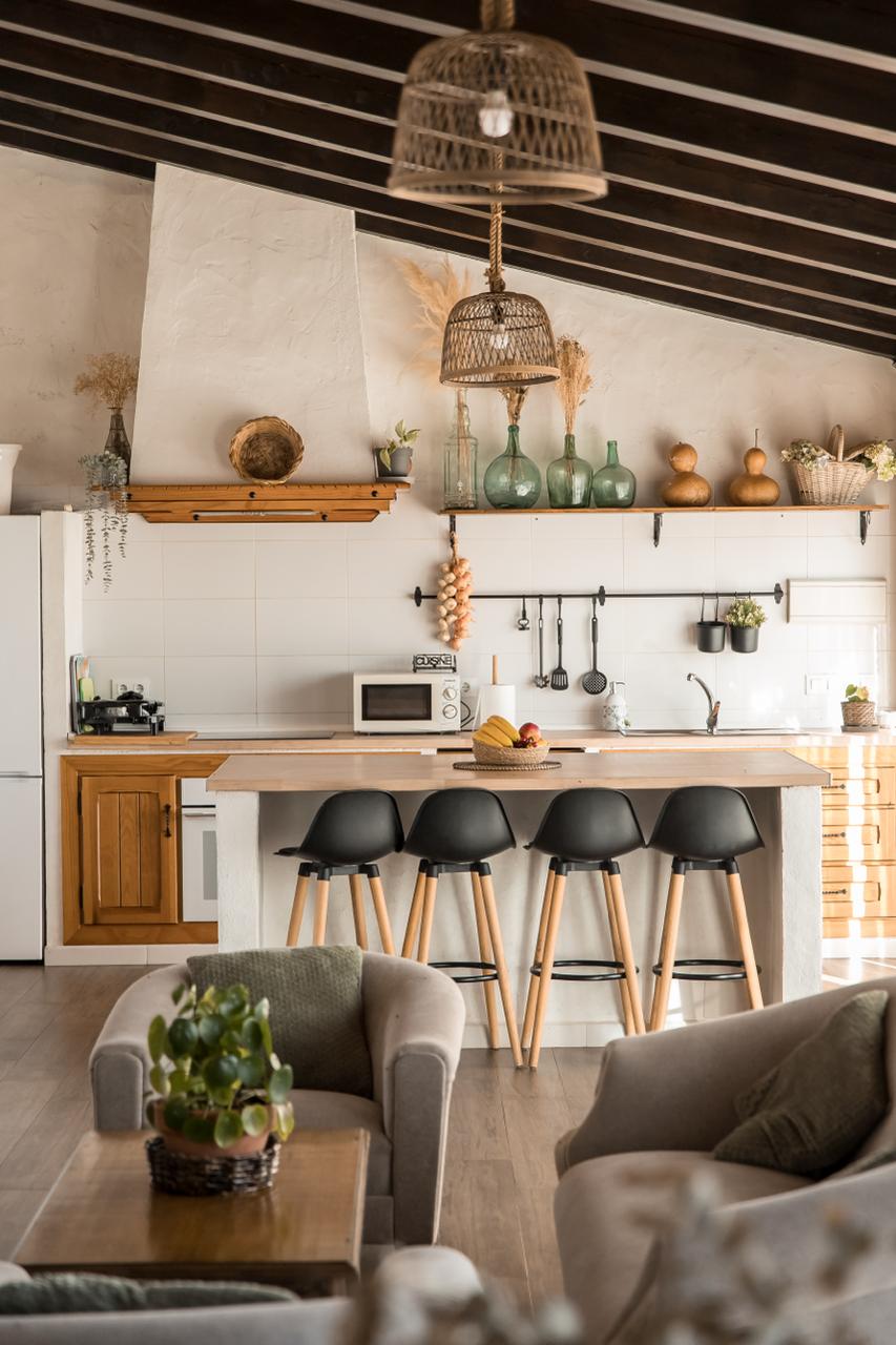 Kitchen bar with black stools and an open shelf of glass demijohns.