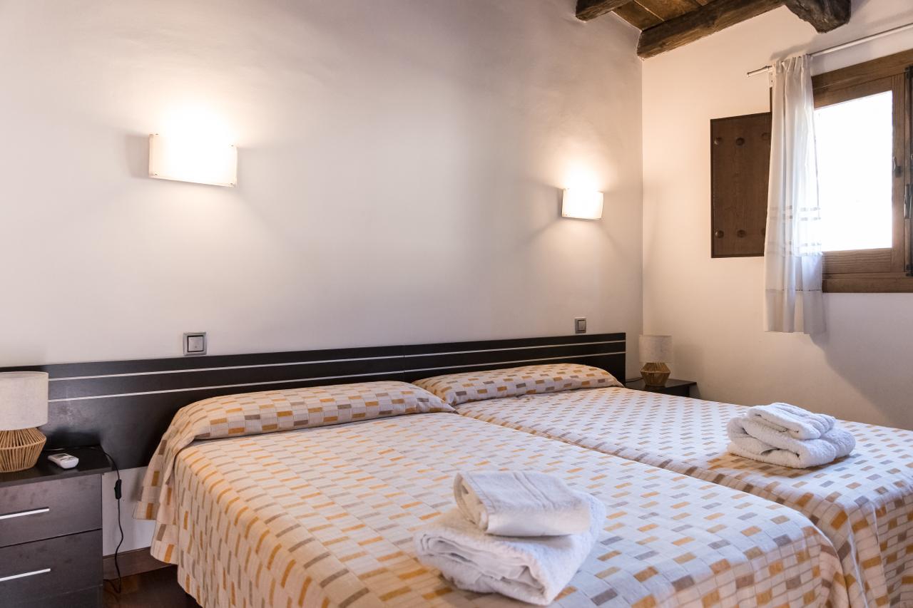 Twin beds with wall lights and folded towels.