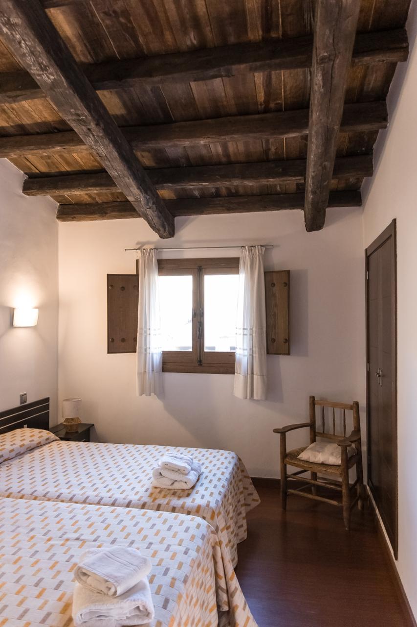 Twin bedroom with heavy beamed ceiling, shuttered window and wardrobe.