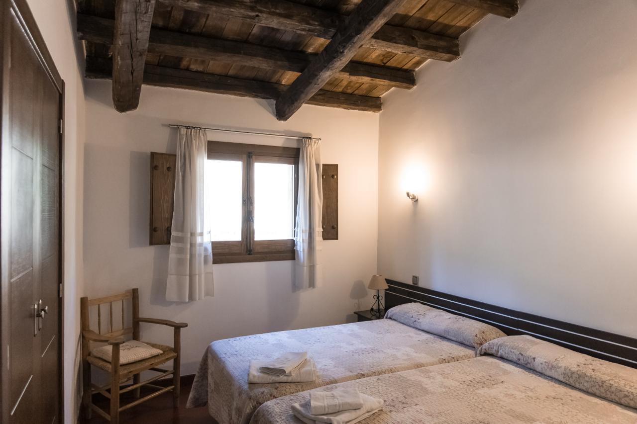 Second twin bedroom with a wooden chair by the window.