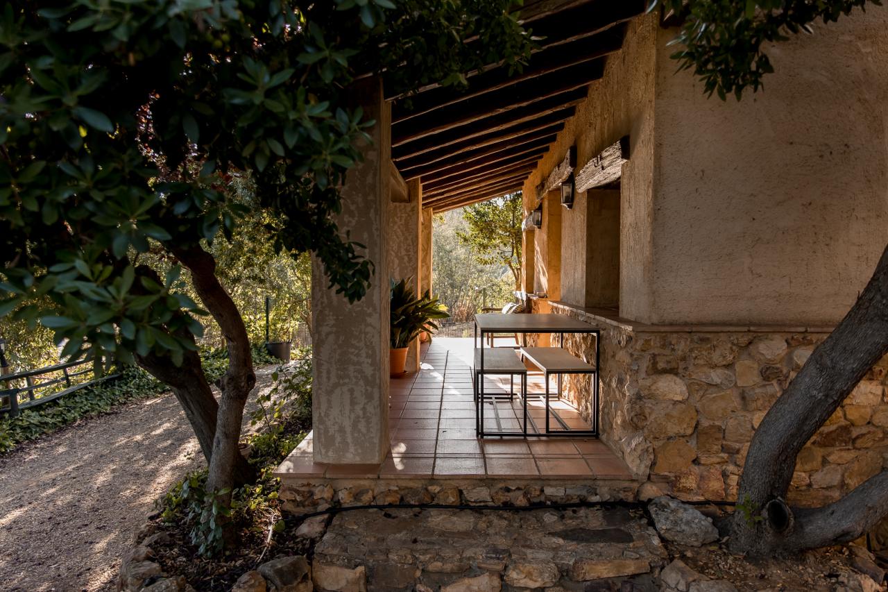 Covered terrace walkway with a high table and stools.